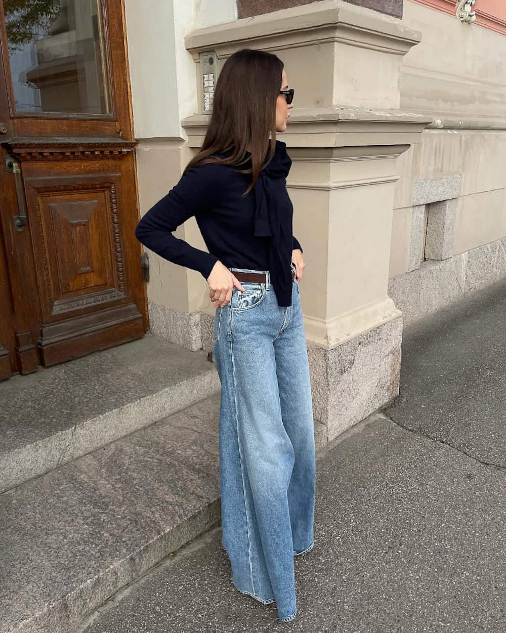 Woman wearing medium wash wide leg jeans and a black sweater.