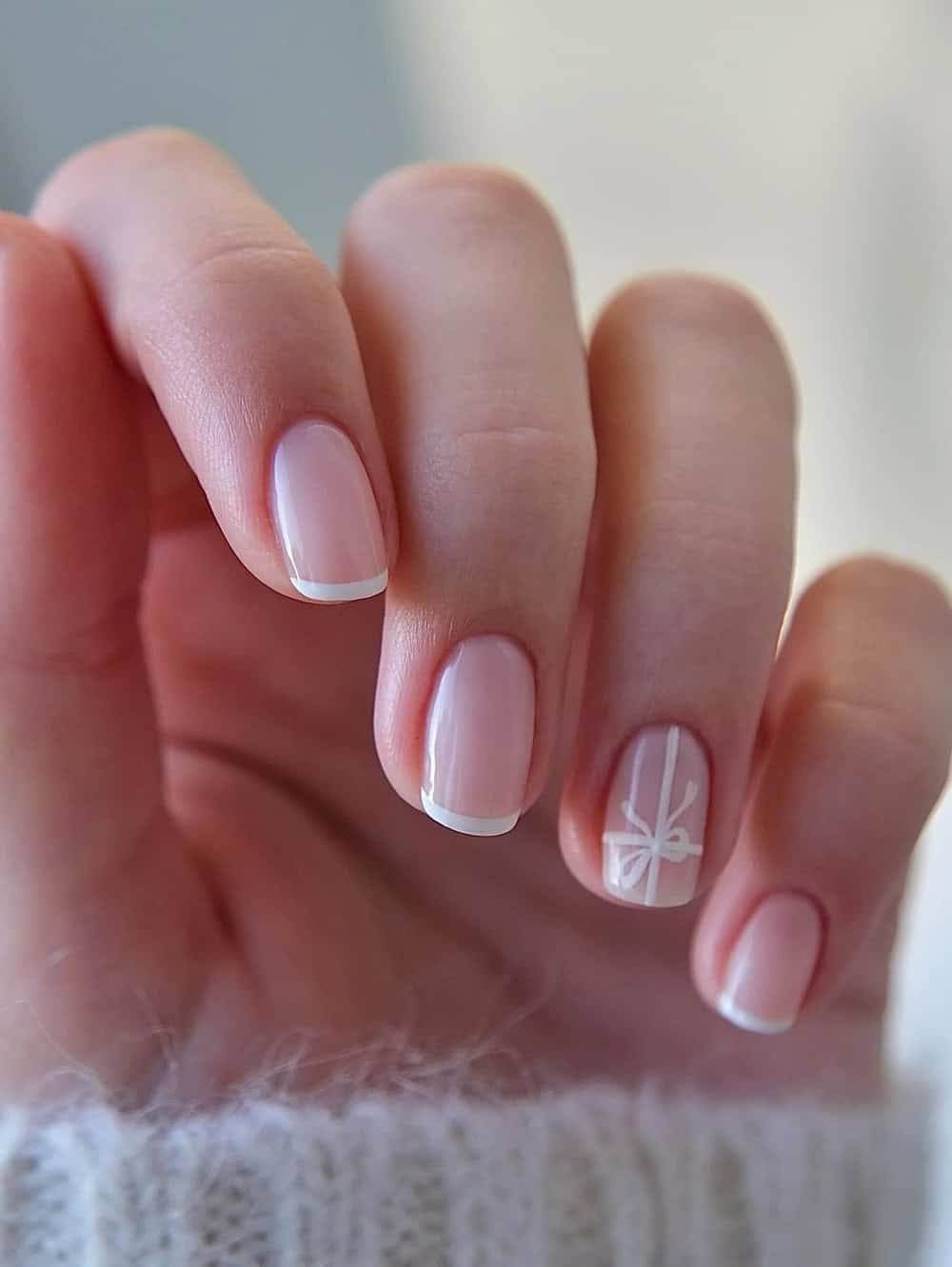 short nude nails with white tips and a gift wrapped accent nail