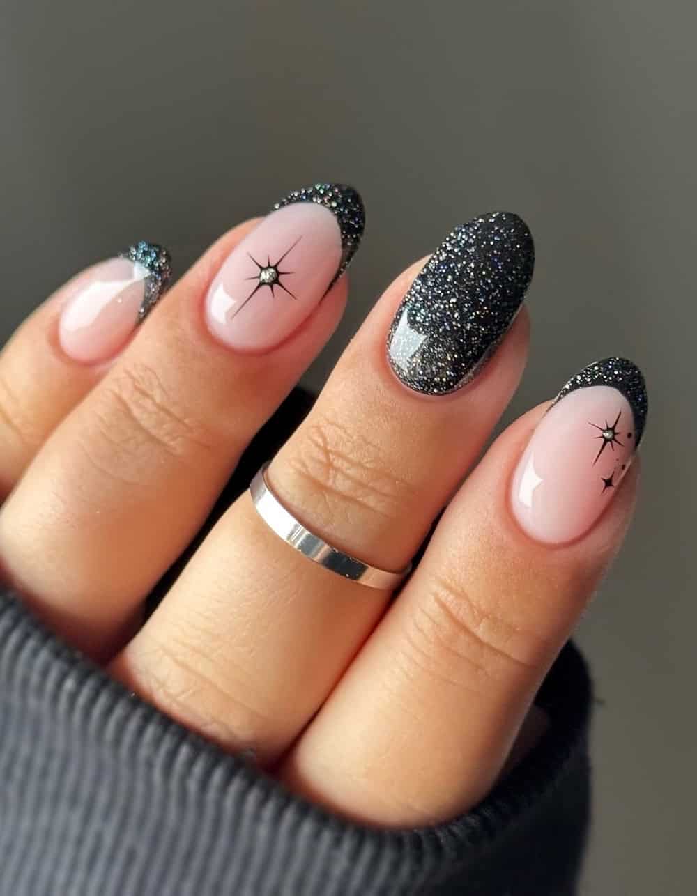 short nude nails with black glitter polish and sparkle accents