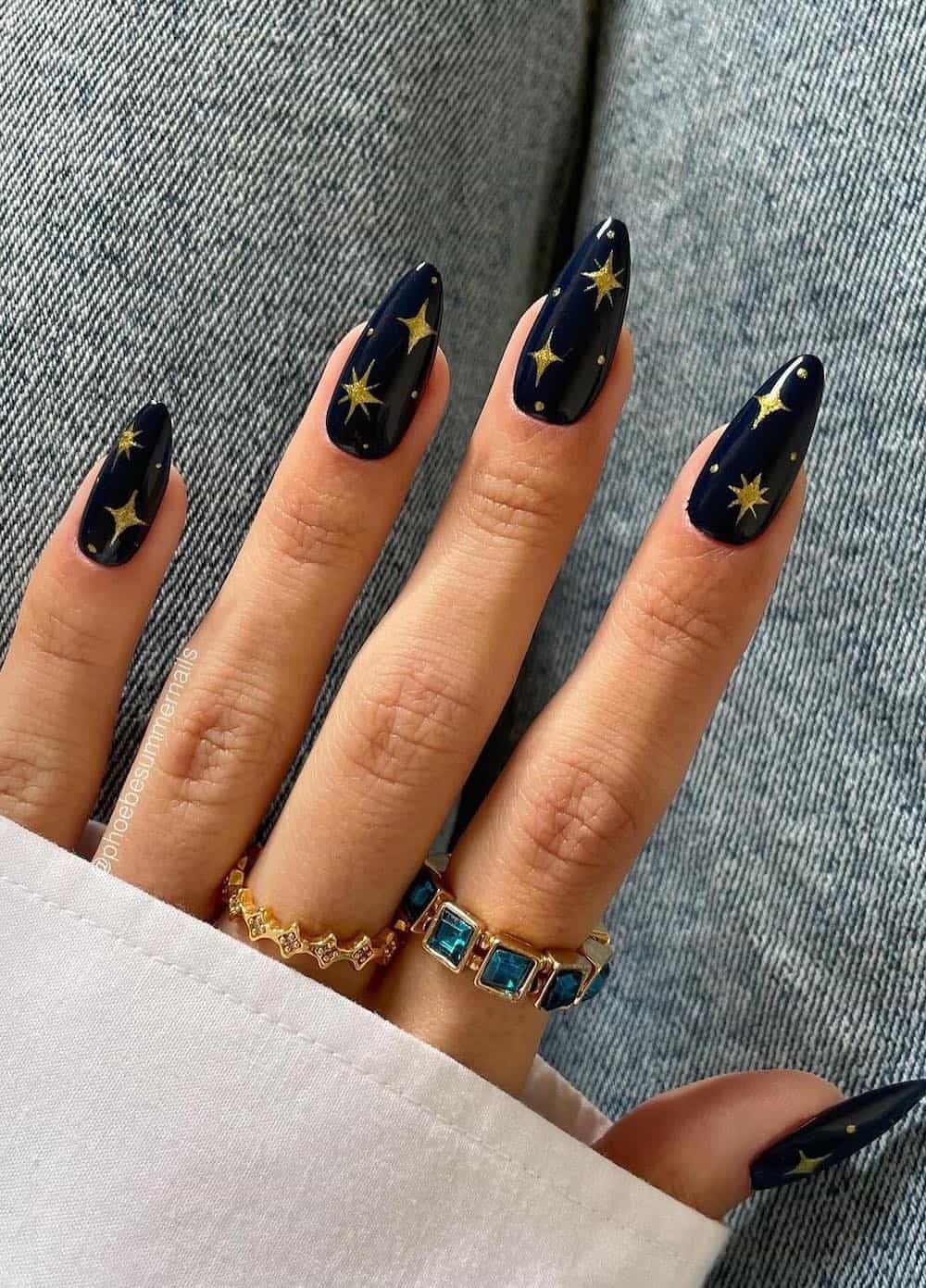 long navy almond nails with gold star and sparkle art