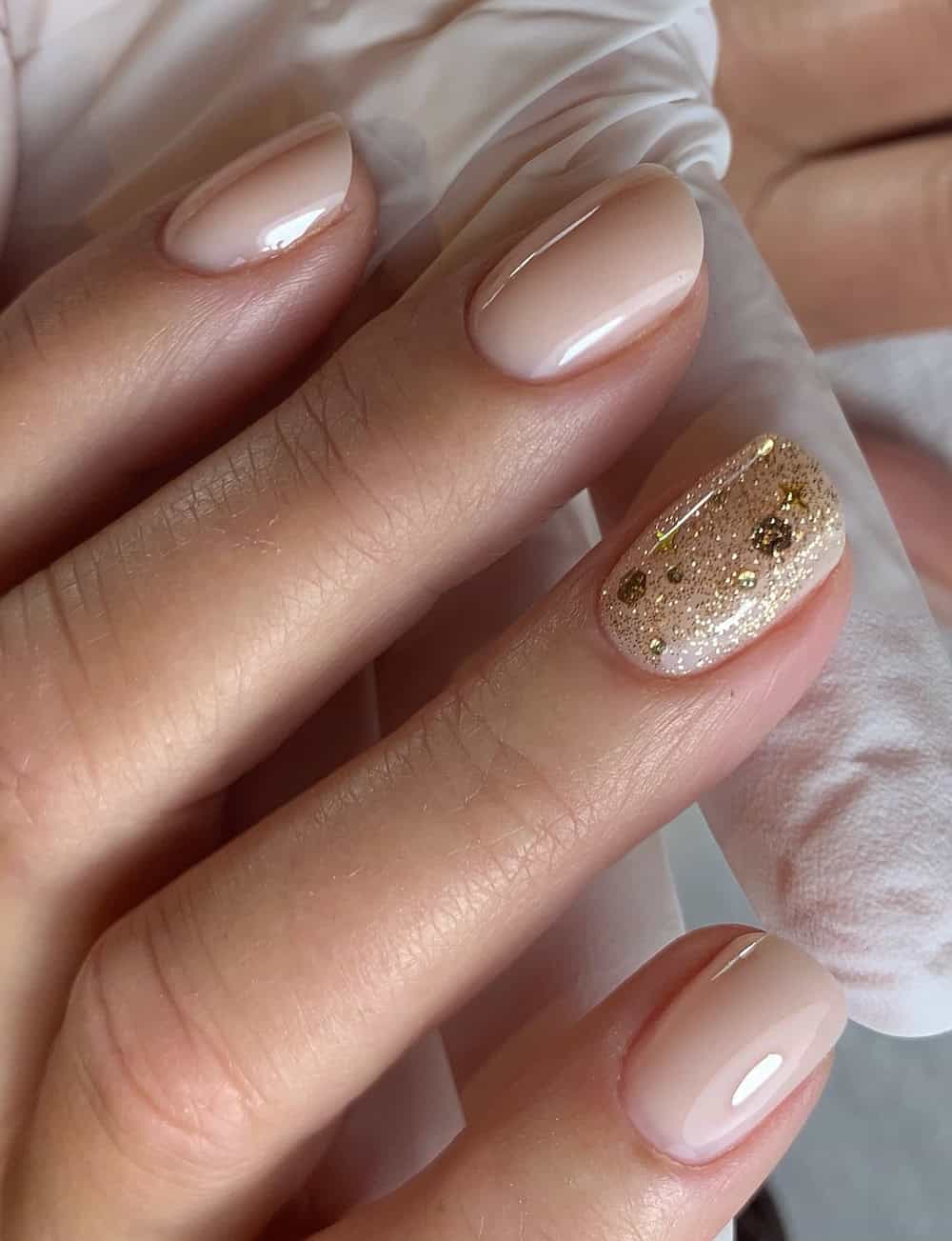 short nude nails with gold glitter accent nail