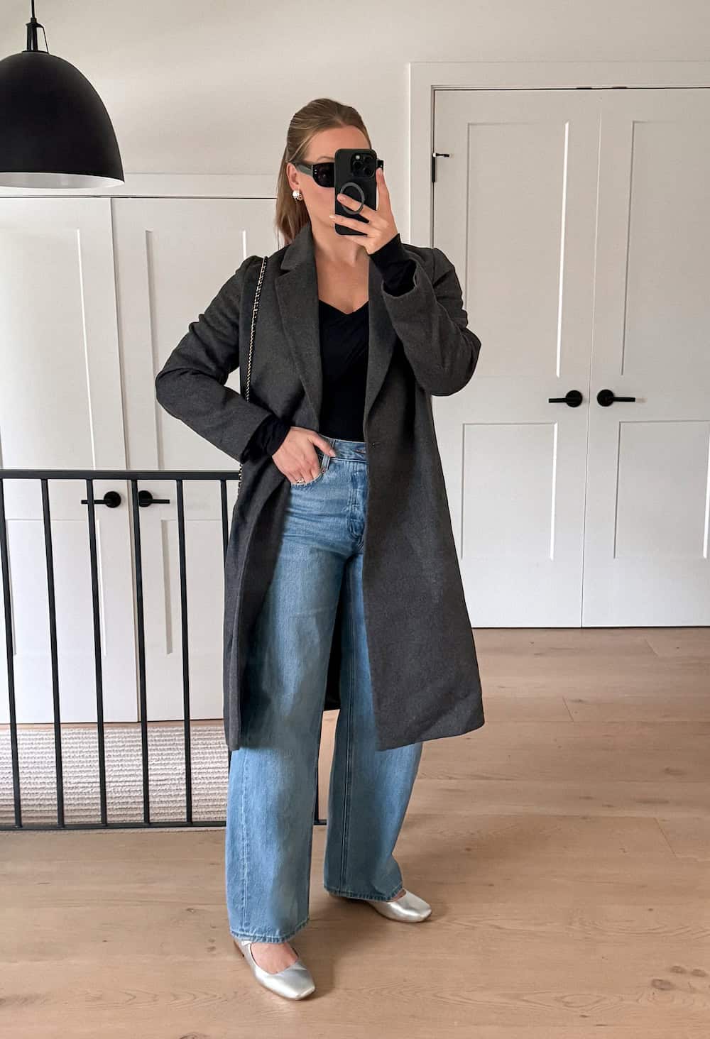 Christal wearing jeans, flats and a long charcoal coat.