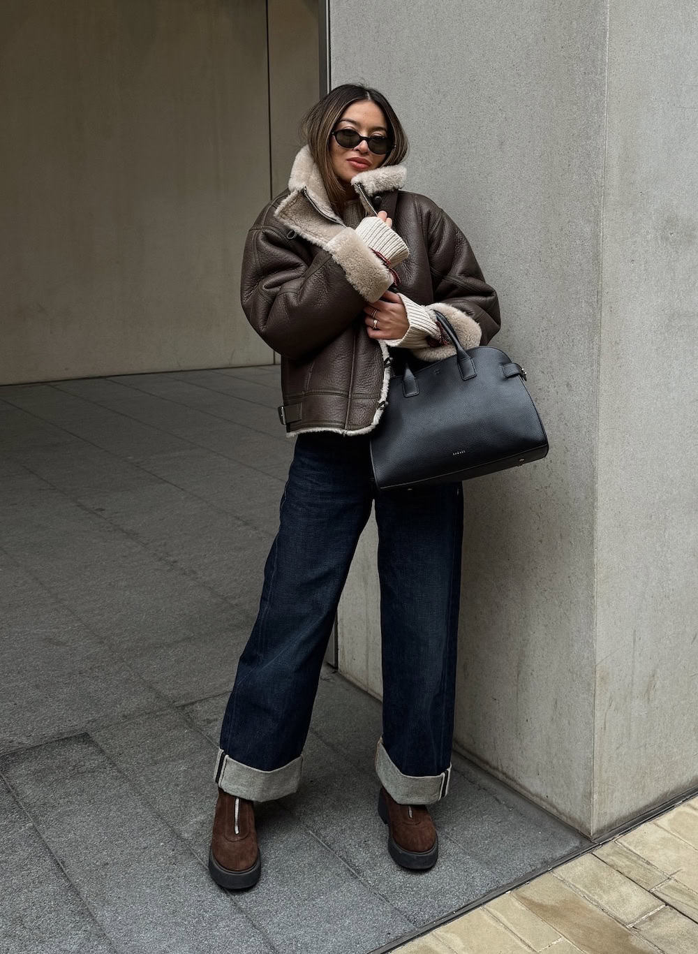 Woman wearing jeans, chunky boots and a leather jacket.